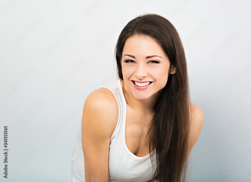 Beautiful chuckling woman in casual white t-shirt and long hair on blue background. Closeup Beautiful chuckling woman in casual white t-shirt and long hair on blue background. Closeup