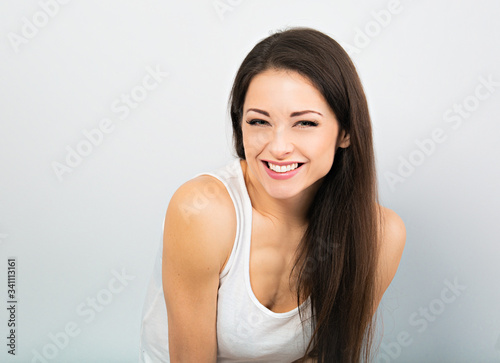Beautiful chuckling woman in casual white t-shirt and long hair on blue background. Closeup © nastia1983