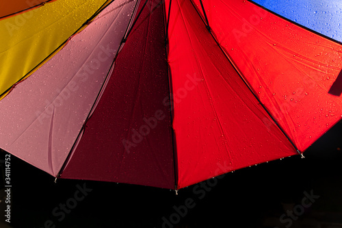 A multi colored rainbow umbrella with rain running down its sides