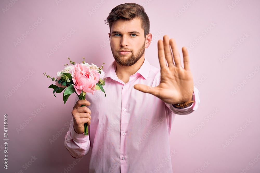 Young blond romantic man with beard and blue eyes holding beautiful bouquet of flowers with open hand doing stop sign with serious and confident expression, defense gesture Young blond romantic man with beard and blue eyes holding beautiful bouquet of flowers with open hand doing stop sign with serious and confident expression, defense gesture
