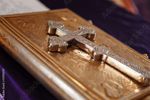 Golden gospel (holy bible) book and a silver cross on it. Russian eastern orthodox church.