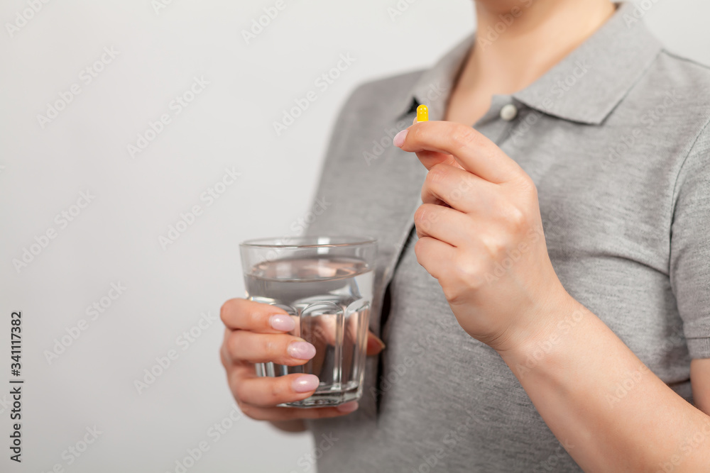 Female hands hold pills and a stock of water. Health care, medical supplement concept. Sick girl holding medicine to recover Female hands hold pills and a stock of water. Health care, medical supplement concept. Sick girl holding medicine to recover