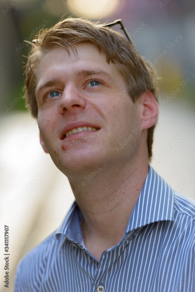 Face of happy young blond businessman thinking in the streets outdoors Face of happy young blond businessman thinking in the streets outdoors