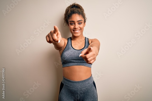 Young african american sportswoman doing sport wearing sportswear over white background pointing to you and the camera with fingers, smiling positive and cheerful