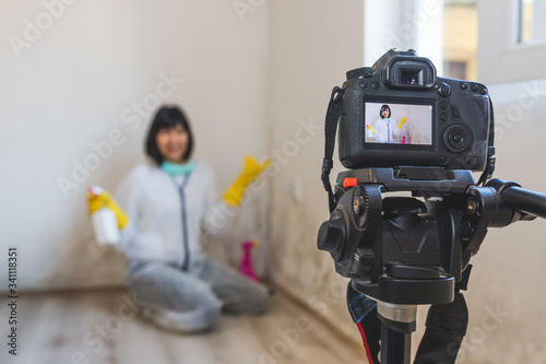 Video camera filming how woman cleaning mold from wall using spray bottle with mold removal products.