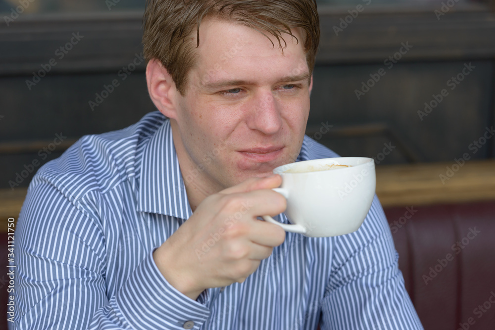 Face of young blond businessman thinking and drinking coffee Face of young blond businessman thinking and drinking coffee