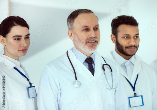 Smiling senior doctor standing with colleagues in clinic