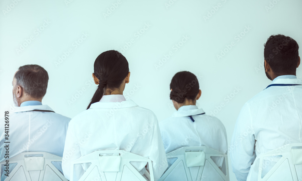 Group of medical workers sitting in front of white wall Group of medical workers sitting in front of white wall