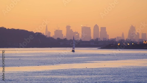 boat sails up the Thames towards London as the sunsets