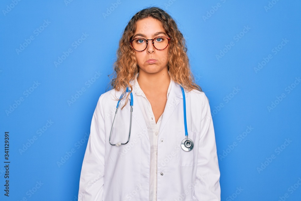Young beautiful blonde doctor woman with blue eyes wearing coat and stethoscope depressed and worry for distress, crying angry and afraid. Sad expression. Young beautiful blonde doctor woman with blue eyes wearing coat and stethoscope depressed and worry for distress, crying angry and afraid. Sad expression.