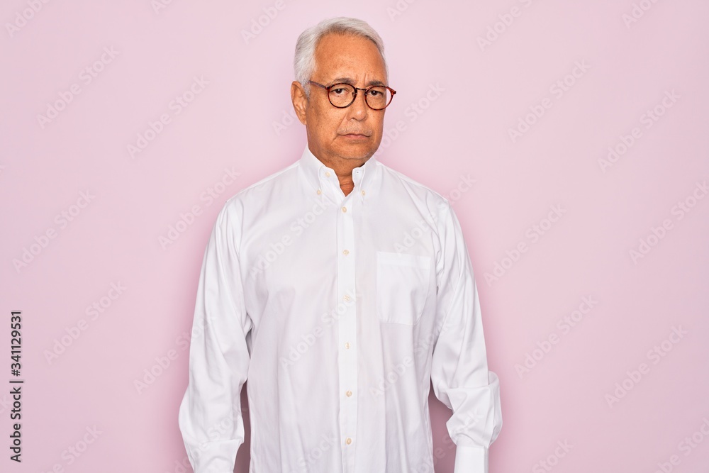 Middle age senior grey-haired man wearing glasses and business shirt over pink background skeptic and nervous, frowning upset because of problem. Negative person. Middle age senior grey-haired man wearing glasses and business shirt over pink background skeptic and nervous, frowning upset because of problem. Negative person.