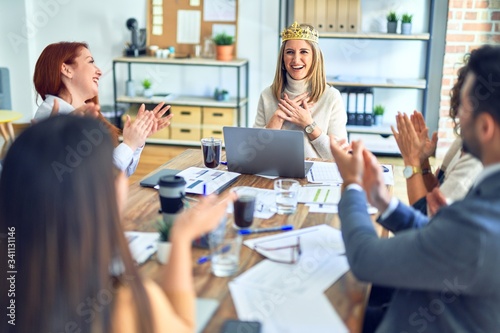 Group of business workers smiling happy and confident. Working together with smile on face applauding one of them wearing king crown at the office