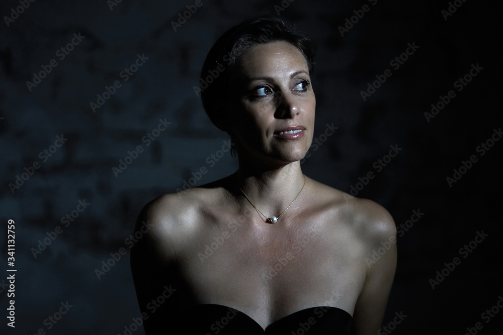 A half-naked sexy woman smiles beautifully and looks towards the light in a dark room. A half-naked sexy woman smiles beautifully and looks towards the light in a dark room.