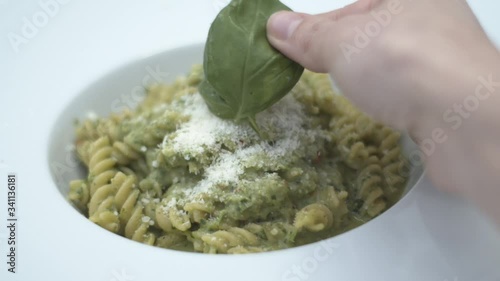 Mettere del basilico su pasta integrale al sugo di prezzemolo e parmigiano reggiano