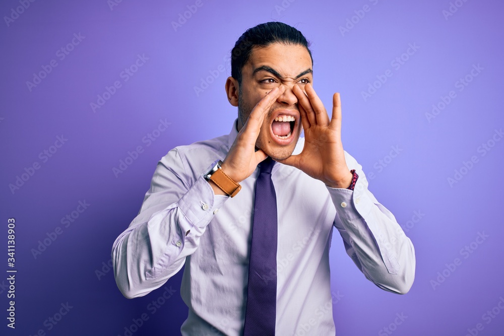 Young brazilian businessman wearing elegant tie standing over isolated purple background Shouting angry out loud with hands over mouth Young brazilian businessman wearing elegant tie standing over isolated purple background Shouting angry out loud with hands over mouth