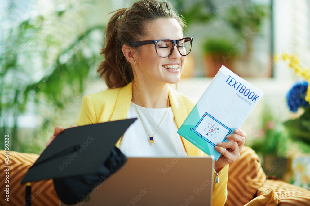 happy modern woman with graduation cap, laptop and textbook happy modern woman with graduation cap, laptop and textbook