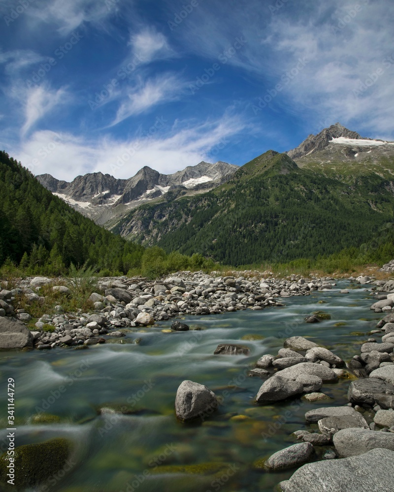 A high mountain river with glaciers in the background in the Italian Alps. Valtellina 