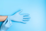 Surgeon putting medical gloves on isolated on blue background