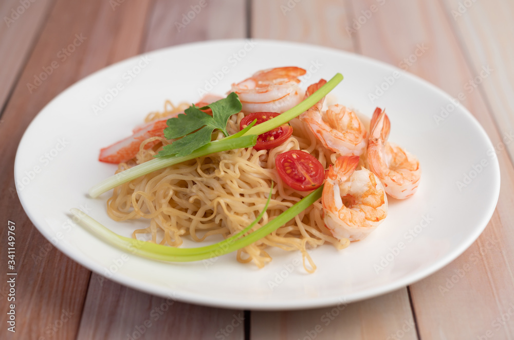 Stir-fried instant noodle with prawn and crab stick along  in a white dish.