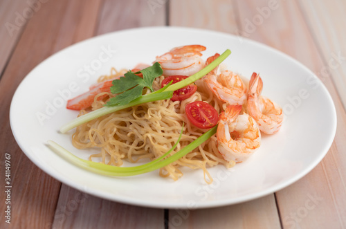 Stir-fried instant noodle with prawn and crab stick along in a white dish.