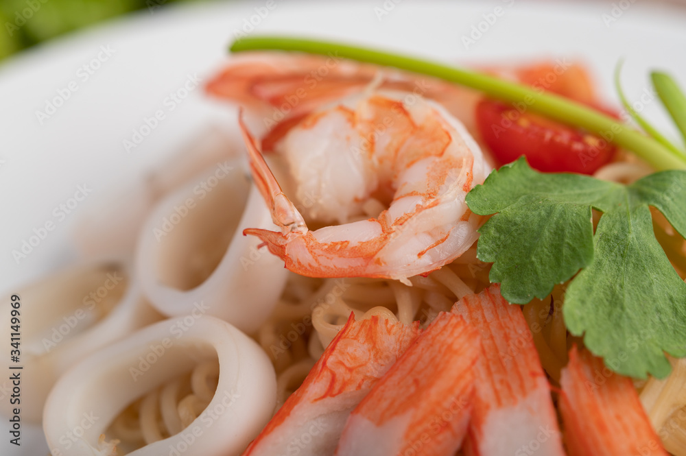 Stir-fried instant noodle with prawn and crab stick along in a white dish. Stir-fried instant noodle with prawn and crab stick along in a white dish.