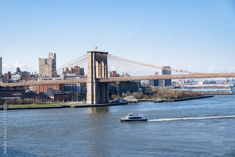 Manhattan skyline with Brooklyn bridge. Sky-rise skyscrapers tall apartment buildings. Dramatic cloudy sky with sun rays. 