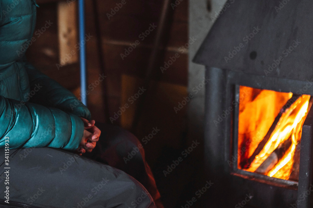 Woman warming up near a fireplace in a hut