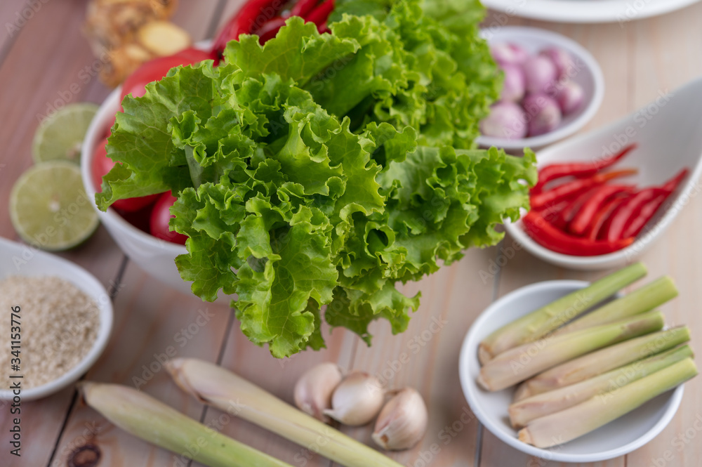 Red onions, lemon, lemongrass, chilies, garlic, galangal, and lettuce in a cup on a wooden floor. Red onions, lemon, lemongrass, chilies, garlic, galangal, and lettuce in a cup on a wooden floor.
