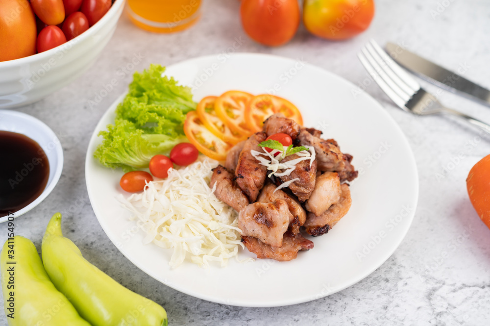 Grilled pork cutlet with tomatoes and salad, arranged in a white dish.