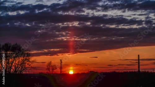 Timelapse of a beautiful sunset with clouds backlit by the sun, in the evening, against the backdrop of a natural landscape and a wide-angle panorama with elements of an industrial landscape photo