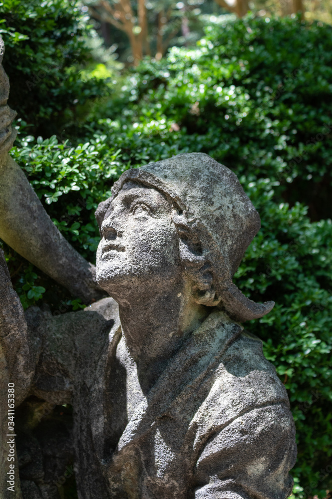 Garden statue of a boy looking up, sunlit face, vertical aspect Garden statue of a boy looking up, sunlit face, vertical aspect