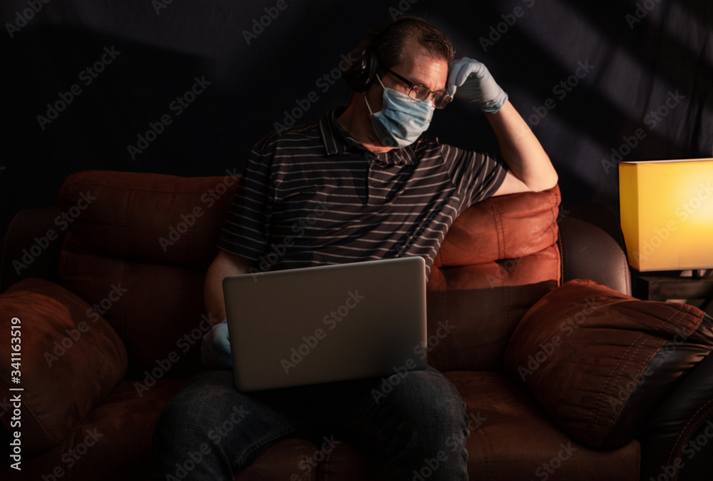Middle aged man working at home on his computer for the coronavirus using protective equipment such as gloves and mask Middle aged man working at home on his computer for the coronavirus using protective equipment such as gloves and mask