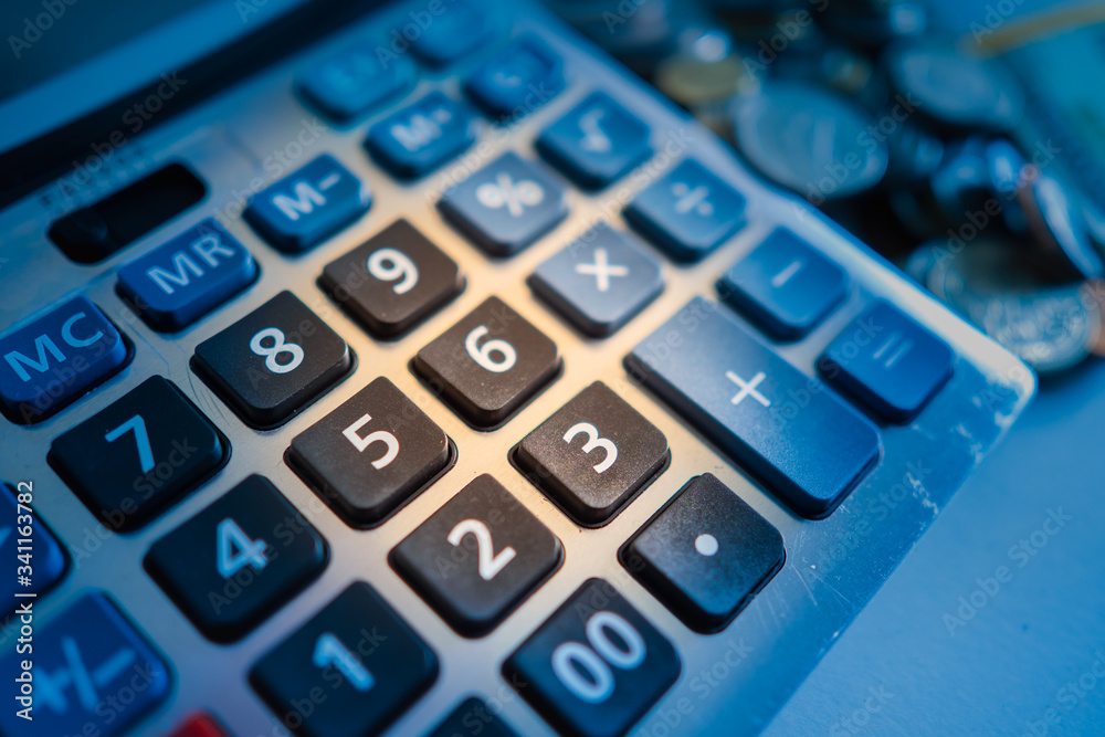 Calculator close-up on the background of coins. Calculation of income and expenses. Financial calculation. Budget planning. Expenditure of means. Consumption and saving. Calculator close-up on the background of coins. Calculation of income and expenses. Financial calculation. Budget planning. Expenditure of means. Consumption and saving.