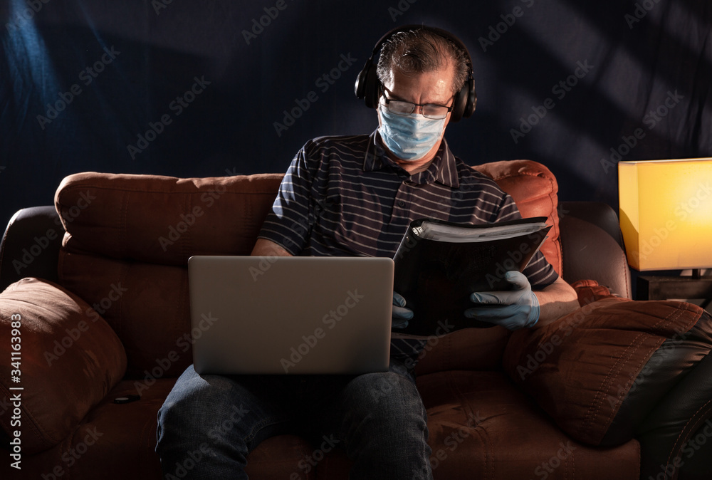 Middle aged man working at home on his computer for the coronavirus using protective equipment such as gloves and mask Middle aged man working at home on his computer for the coronavirus using protective equipment such as gloves and mask
