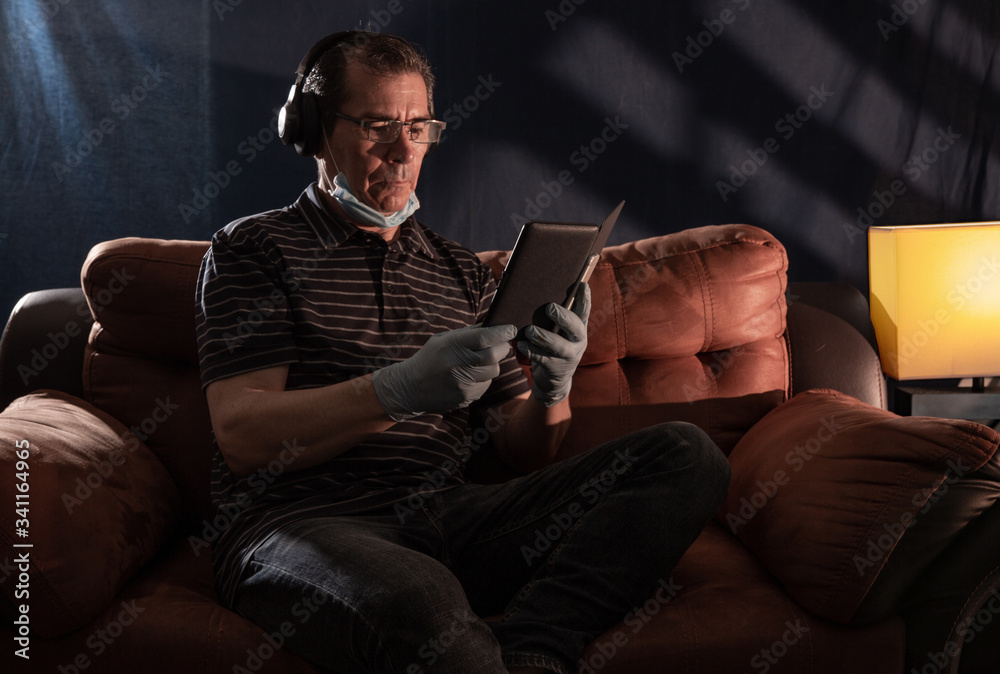 Middle aged man working at home on his computer for the coronavirus using protective equipment such as gloves and mask Middle aged man working at home on his computer for the coronavirus using protective equipment such as gloves and mask
