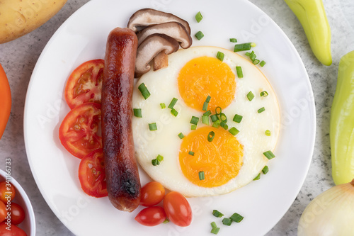 Breakfast consisting of bread, fried eggs, tomatoes, Chinese sausage and mushrooms.