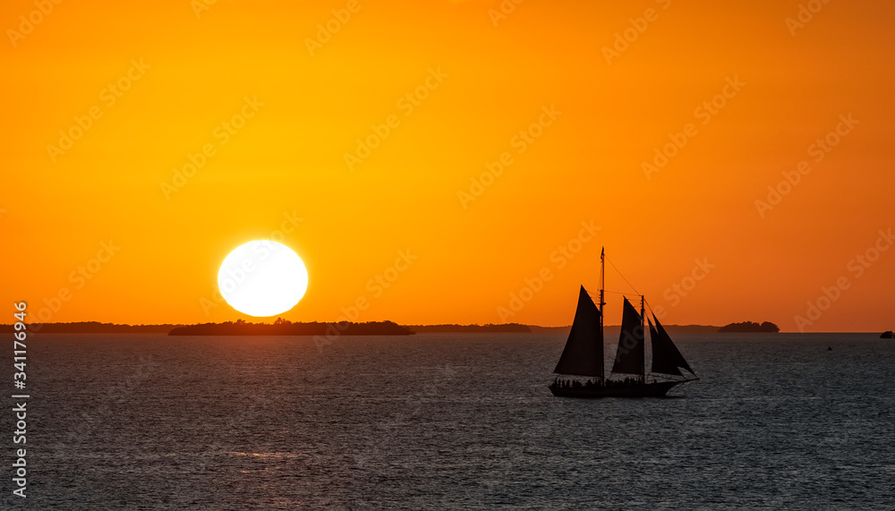 Sailboat at sunset by the coast of Key West with the Sun setting down in the background