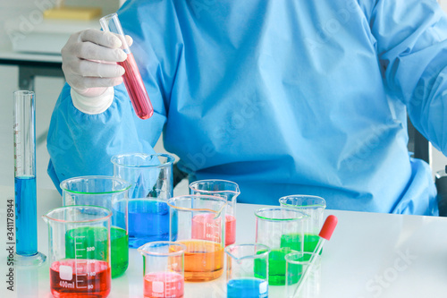 Scientist hand doing science experiment, colorful solutions in scientific glassware on table, researcher working in biology and chemistry laboratory concept