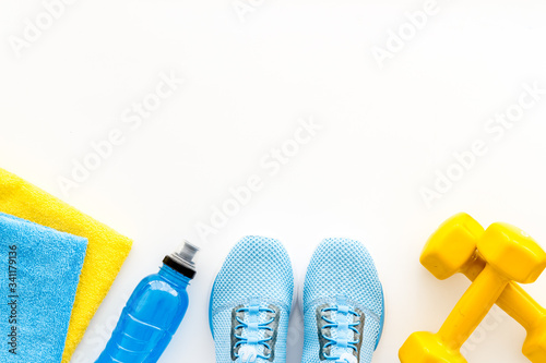 Athletics background with dumbbells, towel, sneakers on white background top view copy space