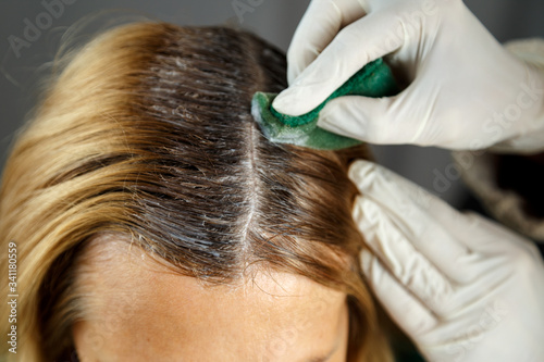 Hairdresser dyes woman's hair in a beauty salon.