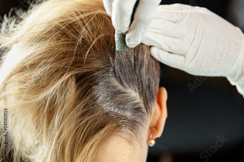 Hairdresser dyes woman's hair in a beauty salon.