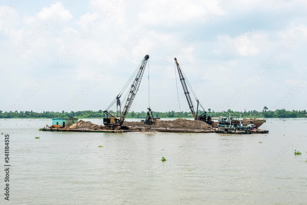 Exploiting sands on the Mekong River. Boats carrying sand on the river in Vinh Long, Vietnam.