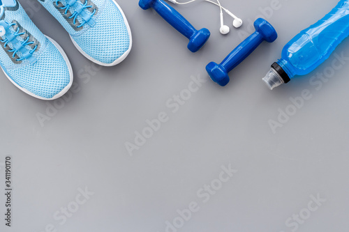 Crossfit set with dumbbells, headphones and sneakers on grey background top-down copy space