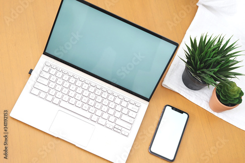 Blank open laptop and black smartphone mock-up corporate on wood desk