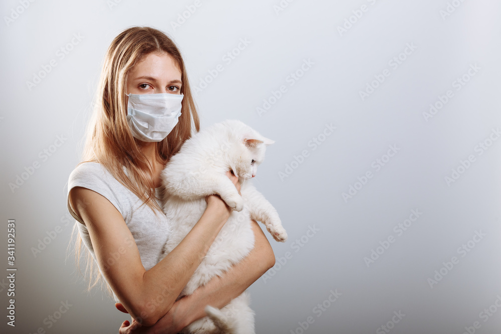 Yound lady in protective surgical mask holds cat pet in face mask. Chinese Coronavirus disease COVID-19 is dangerous for pets Yound lady in protective surgical mask holds cat pet in face mask. Chinese Coronavirus disease COVID-19 is dangerous for pets