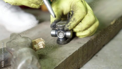 mechanic using punch during repair of steering joint with cross bearing