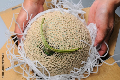 箱に入ったメロンを取り出す手です