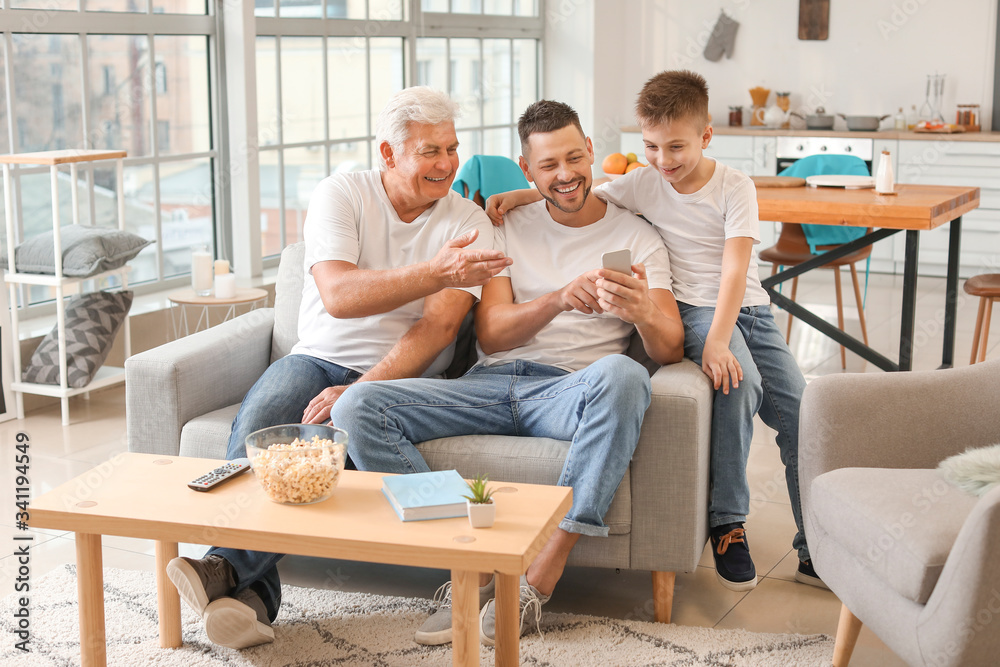 Man with his father and son using mobile phone at home Man with his father and son using mobile phone at home