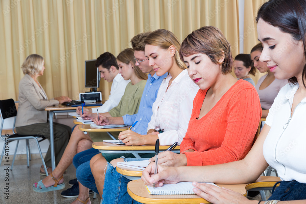 Fototapeta premium Side view of young people with female lecturer in auditorium
