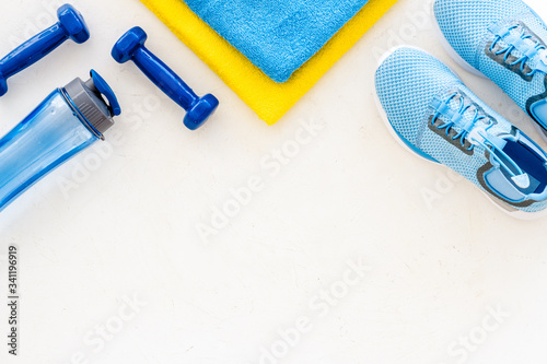Fitness set with sneakers, dumbbells, towel on white background top view copy space